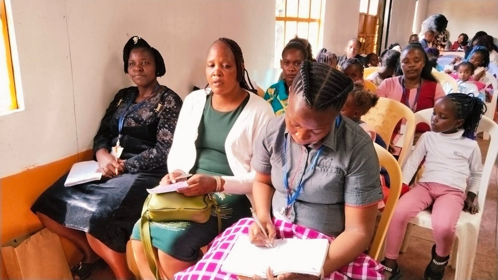 Women and children taking notes during teaching